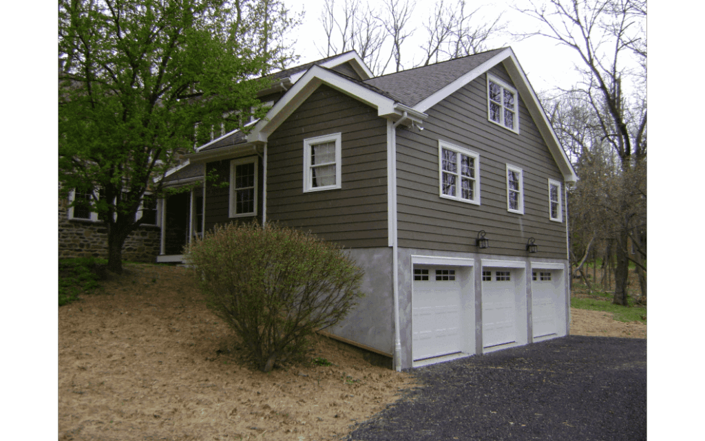 Second-story addition on a small home with brown siding and white trim, with three-car garage beneath.