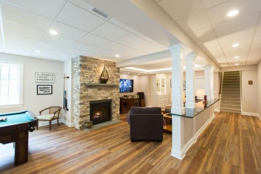 Whole-house renovation with fireplace in stone surround, pool table, tile ceiling, recessed lighting, light wood floors.