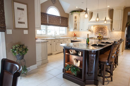 Kitchen remodel in traditional style, with large island, white tile floors, and stone countertops.