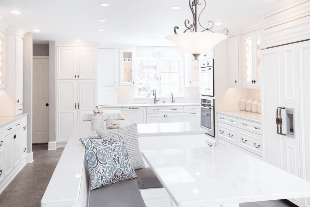 Classic white kitchen with white table, bench seating, and white cabinets.