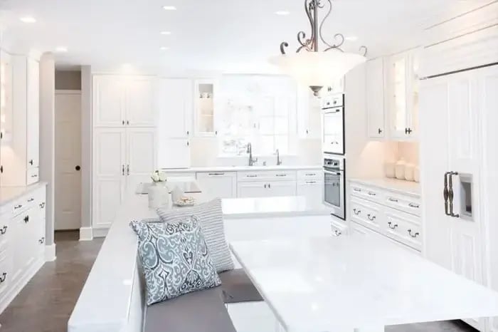 Classic white, light & bright kitchen with stone-top white table with bench seating, and recessed lighting (1)