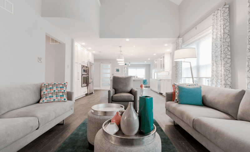 Contemporary remodeled family room with gray couches and colorful pillows. High ceilings, white walls, light wood floors.