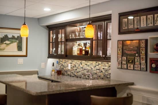 Remodeled basement with a bar area. Stone countertops and yellow pendant lights.