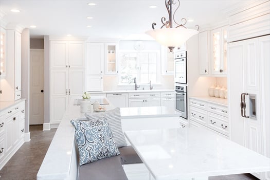Kitchen remodel white cabinets, white stone countertops, and hidden appliances. Bench seating, recessed lighting.