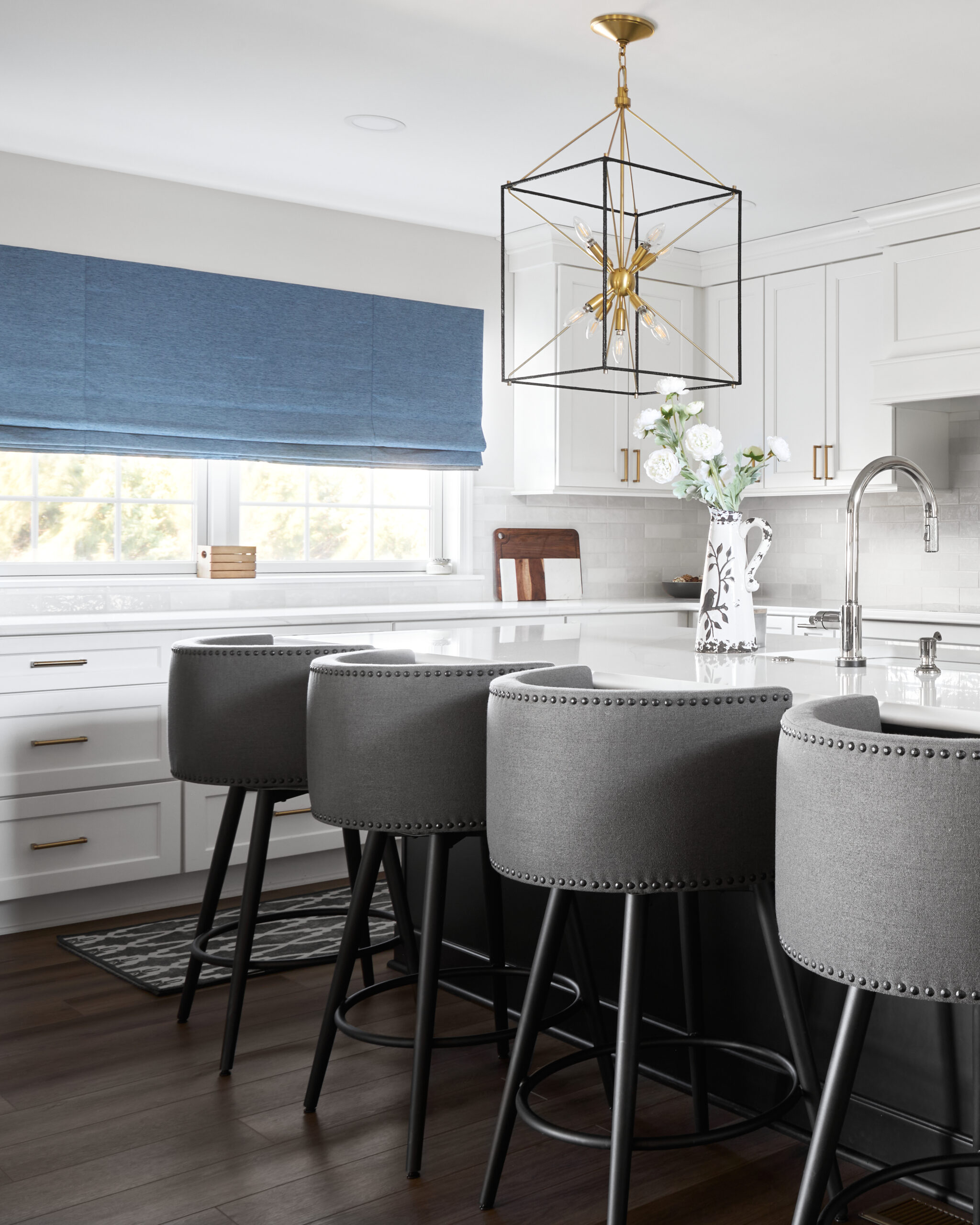 A custom remodeled kitchen with white textured tile backsplash, white cabinets, and white granite countertops.