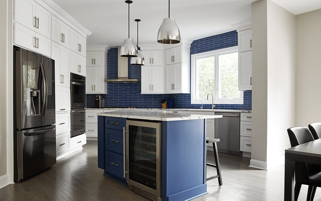 A custom kitchen remodel with blue subway tile backsplash, white cabinets, and an accented blue island.