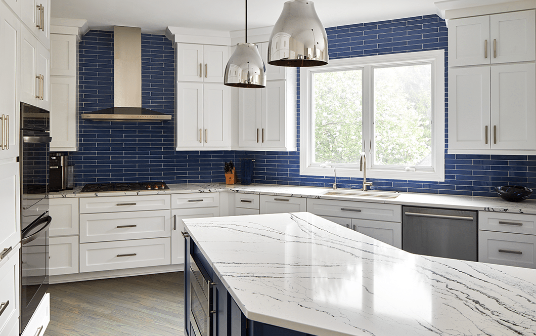A custom kitchen remodel with blue subway tile backsplash, white cabinets, and granite countertops.